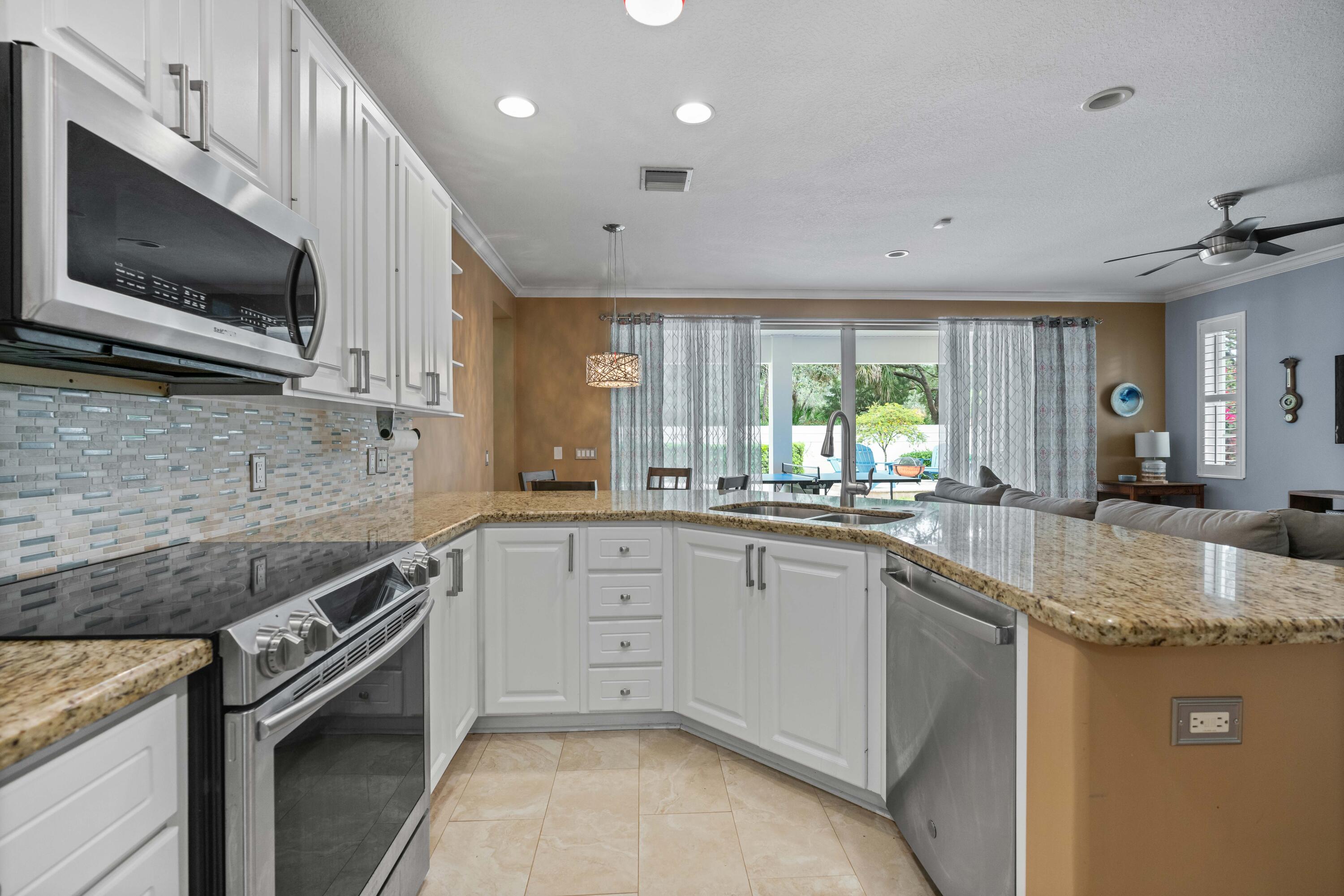 144 Sweet Bay Circle Jupiter, FL 33458 - Photo 22 of 46 a kitchen with granite countertop a sink stainless steel appliances and white cabinets