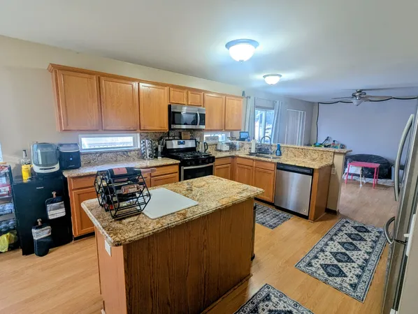 a kitchen with stainless steel appliances granite countertop a sink dishwasher a refrigerator a stove and a refrigerator with wooden floor