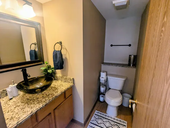 a bathroom with a granite countertop toilet sink and mirror