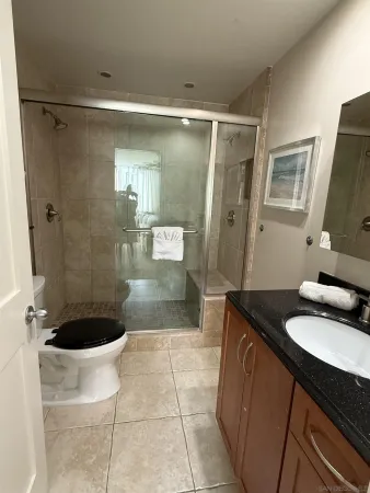 a bathroom with a granite countertop sink a mirror and shower