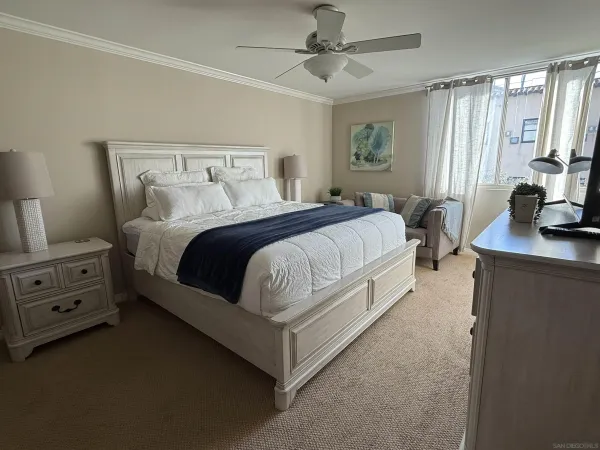 a spacious bedroom with a bed and a flat tv screen on a dresser