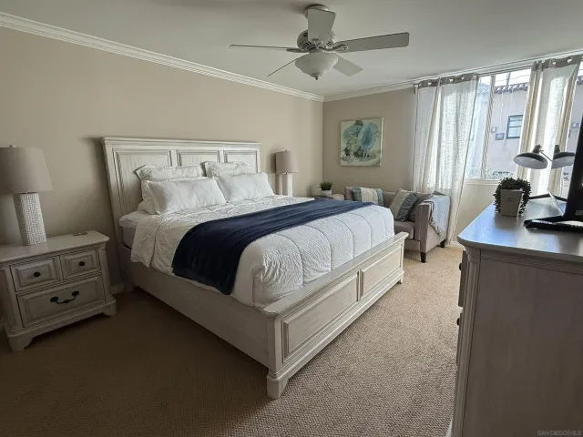 a spacious bedroom with a bed and a flat tv screen on a dresser