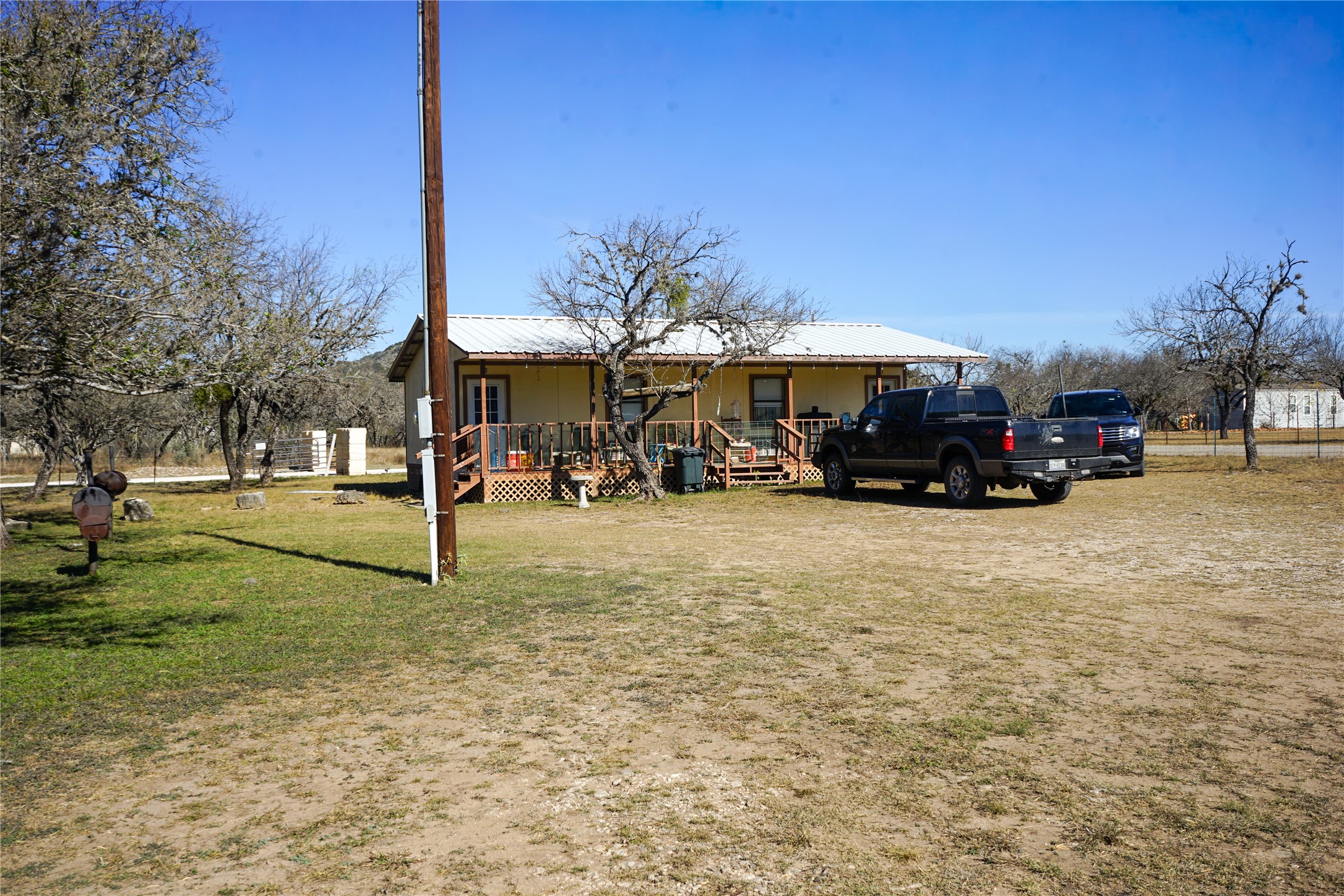 831 Magers Road Concan, TX 78838 - Photo 11 of 39 Back of house with a lawn, a deck, and a metal roof
