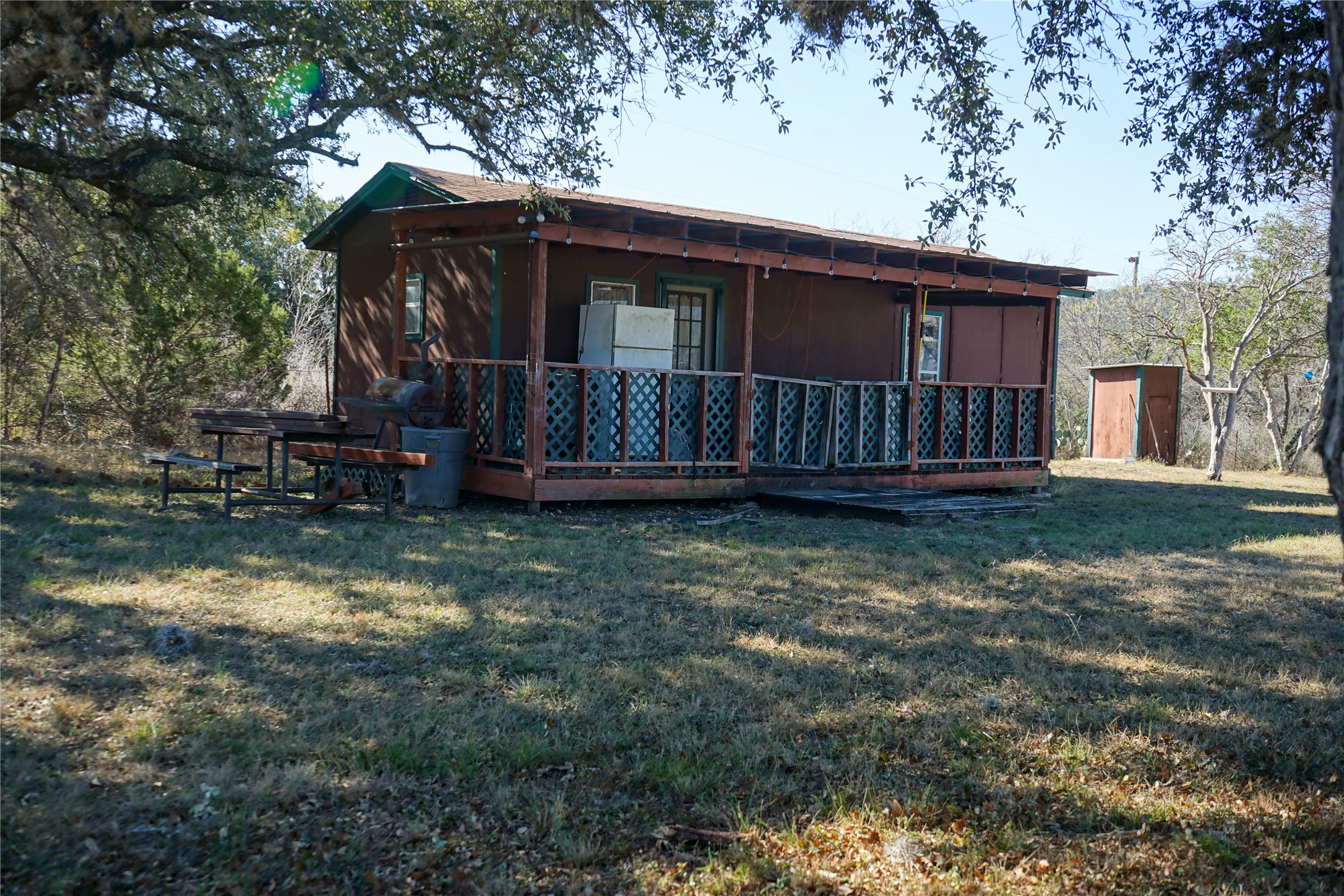 831 Magers Road Concan, TX 78838 - Photo 15 of 39 View of property exterior with a yard, a storage unit, and a wooden deck