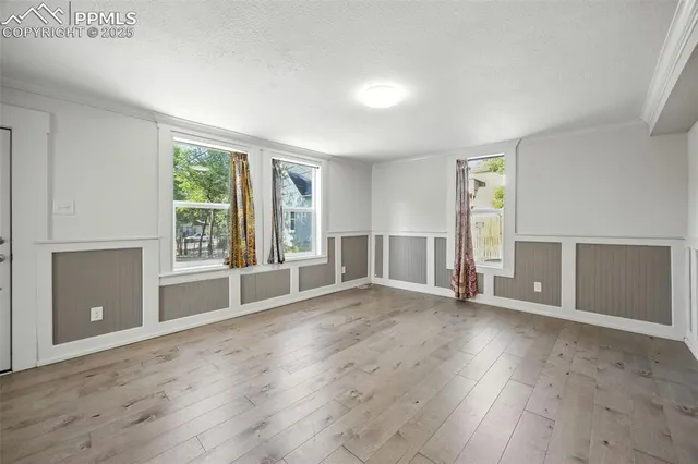 an empty room with wooden floor and windows