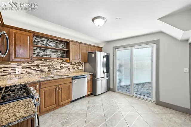 a kitchen with stainless steel appliances granite countertop a stove a sink and a refrigerator