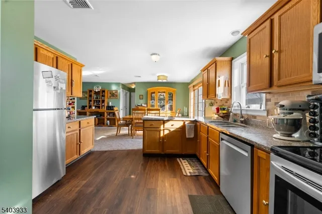 a kitchen with stainless steel appliances granite countertop a refrigerator a oven a sink with wooden floors and cabinets