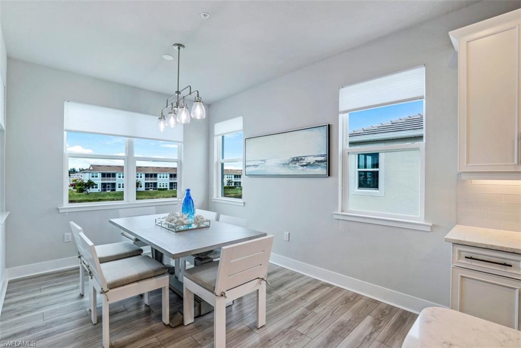 4705 Arboretum Circle, Unit 203 Naples, FL 34112 - Photo 11 of 31 a dining room with furniture a chandelier and wooden floor