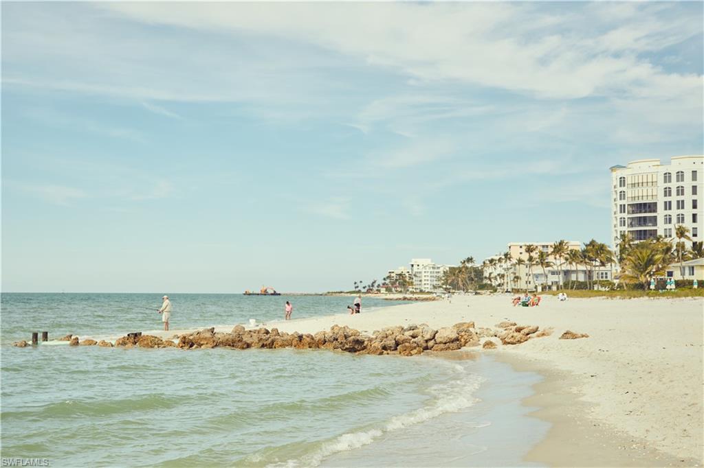 4705 Arboretum Circle, Unit 203 Naples, FL 34112 - Photo 30 of 31 an ocean beach with large trees and buildings in the background