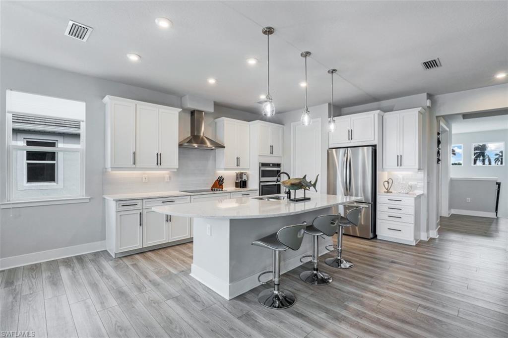4705 Arboretum Circle, Unit 203 Naples, FL 34112 - Photo 6 of 31 a kitchen with stainless steel appliances kitchen island granite countertop a refrigerator a stove a sink dishwasher and a dining table with wooden floor