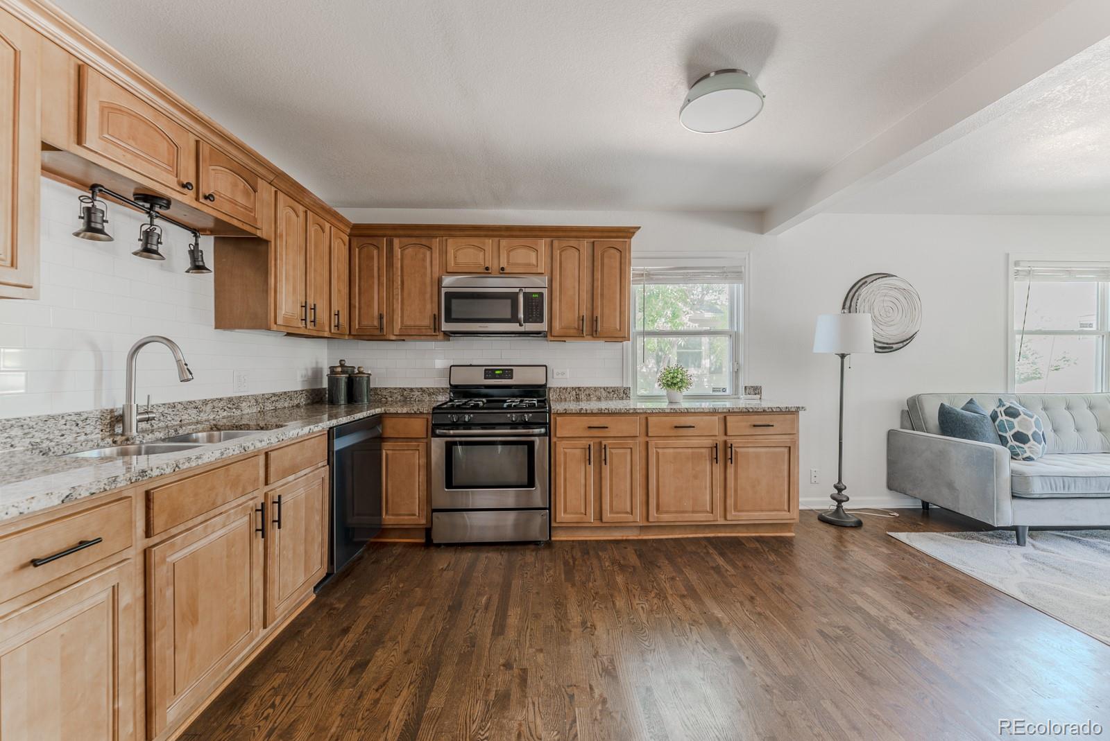 2260 Lilly Drive Thornton, CO 80229 - Photo 11 of 33 a kitchen with granite countertop a sink cabinets and wooden floor