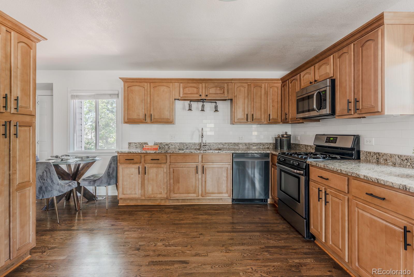2260 Lilly Drive Thornton, CO 80229 - Photo 6 of 33 a kitchen with stainless steel appliances granite countertop a stove top oven a sink dishwasher and white cabinets with wooden floor