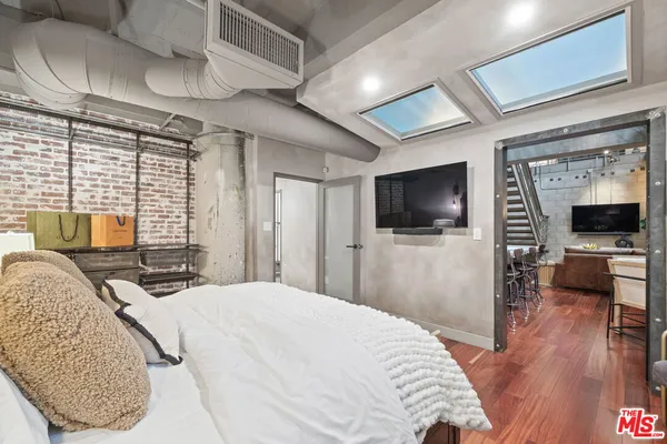 a bedroom with a bed a television and wooden floor