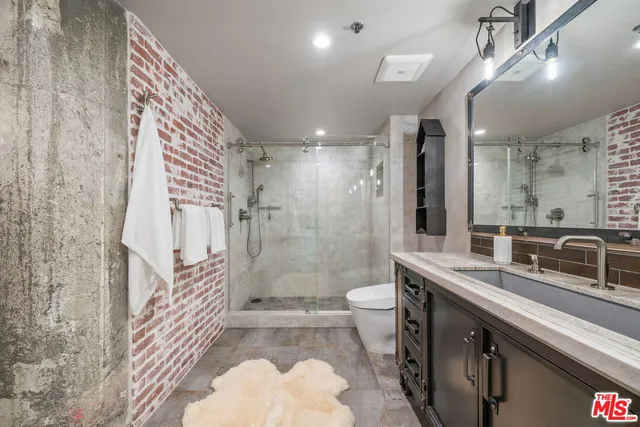 a bathroom with a sink a toilet a mirror and shower