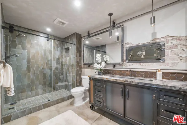 a bathroom with a granite countertop sink toilet a mirror and shower