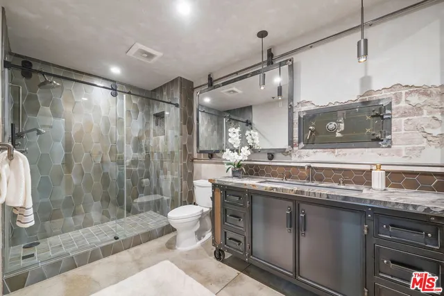 a bathroom with a granite countertop sink toilet a mirror and shower