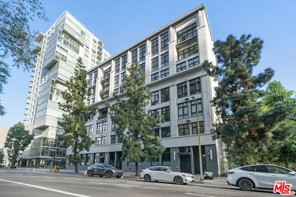 a front view of a building with lot of cars and trees