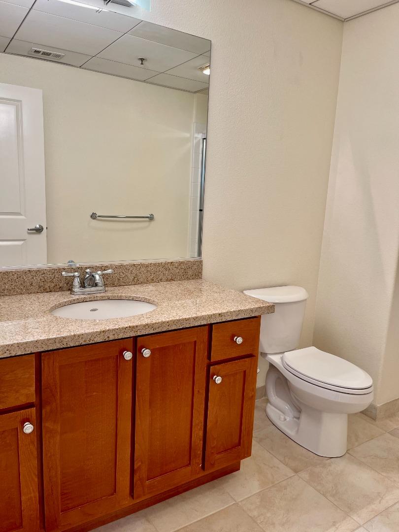 423 7th Street, Unit 516 Oakland, CA 94607 - Photo 15 of 21 a bathroom with a granite countertop toilet sink and mirror