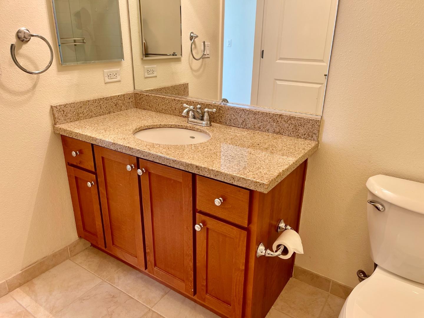 423 7th Street, Unit 516 Oakland, CA 94607 - Photo 17 of 21 a bathroom with a granite countertop sink and a mirror