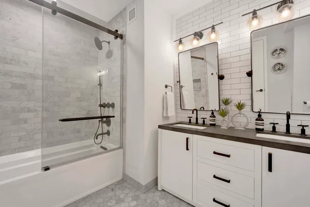 a bathroom with a double vanity sink and mirror with bathtub