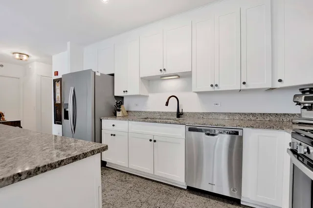 a kitchen with granite countertop white cabinets and refrigerator