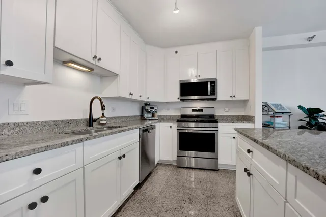 a kitchen with granite countertop white cabinets and a stove