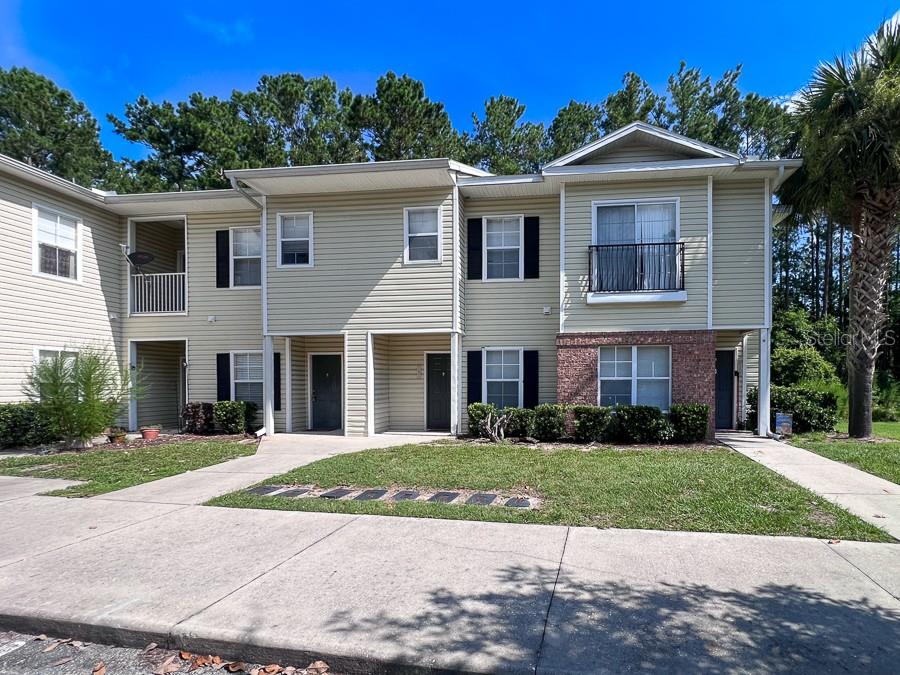 4886 Northwest 46th Place, Unit 106 Gainesville, FL 32606 - Photo 1 of 29 a front view of a house with a yard and potted plants