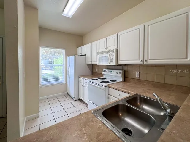 a kitchen with a sink a stove and white cabinets