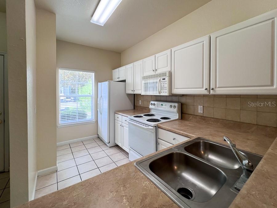 4886 Northwest 46th Place, Unit 106 Gainesville, FL 32606 - Photo 2 of 29 a kitchen with a sink a stove and white cabinets
