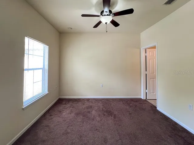 an empty room with windows and fan