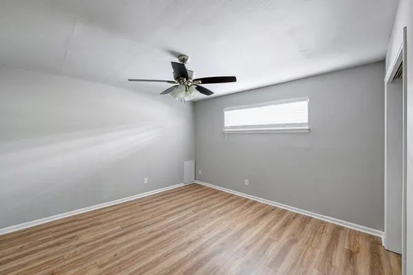 a view of a room with wooden floor closet and ceiling fan