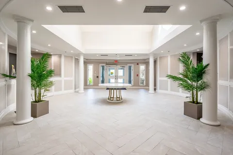 a hallway with a potted plant and couches in it