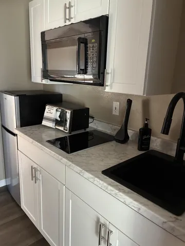 a kitchen with granite countertop cabinets stove top oven and microwave
