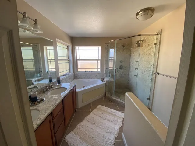 a bathroom with double vanity sink a mirror a bathtub and shower