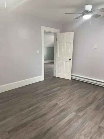 an empty room with wooden floor closet and windows