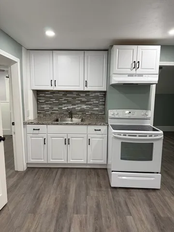 a kitchen with granite countertop a stove and cabinets