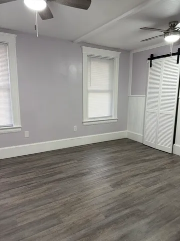 an empty room with wooden floor cabinet and windows