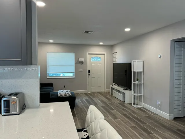 a kitchen with kitchen island a dining table chairs cabinets and wooden floor