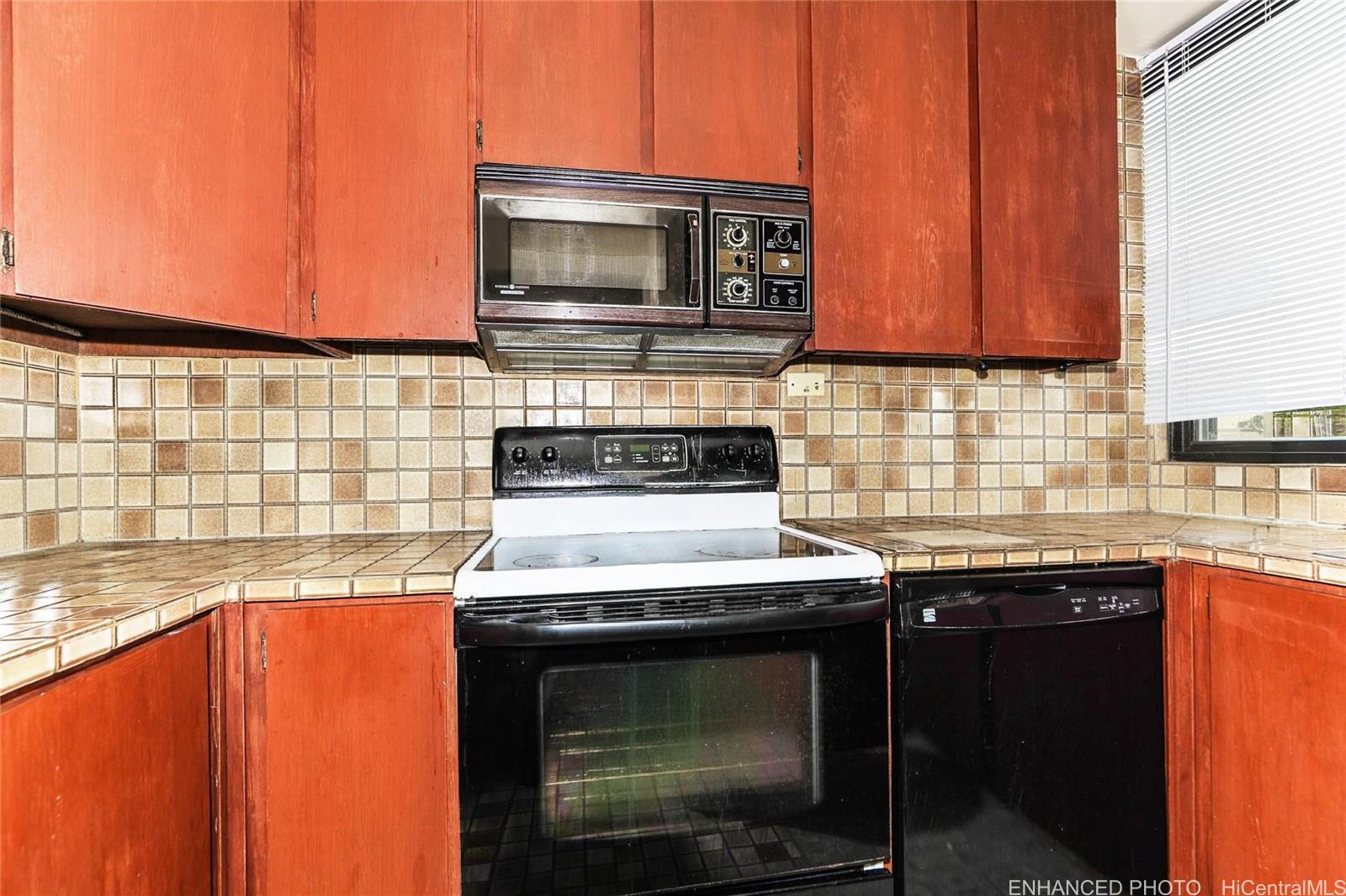 1114 Punahou Street, Unit 3B Honolulu, HI 96826 - Photo 8 of 25 a kitchen with stainless steel appliances a stove a microwave sink and cabinets