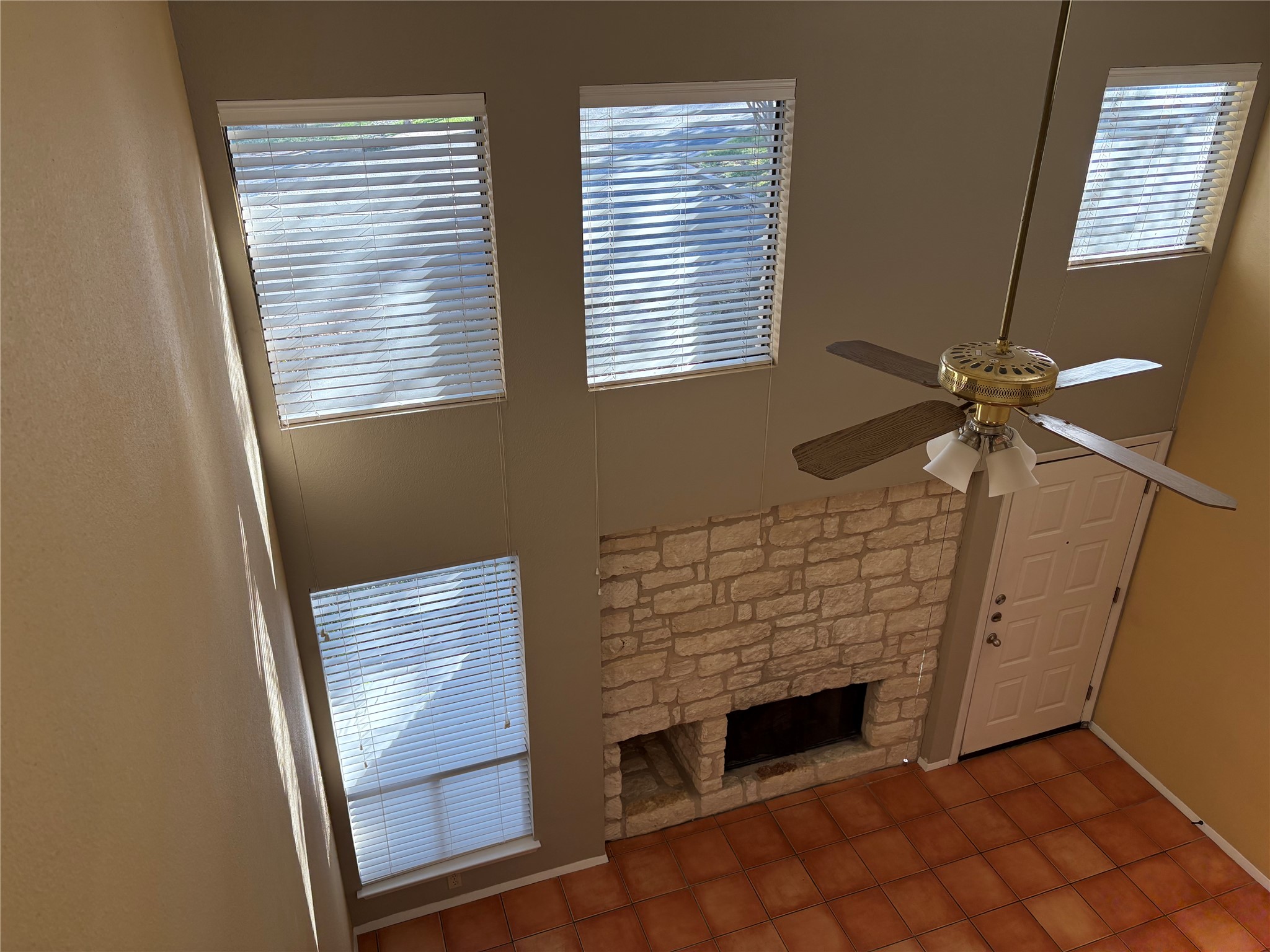 9226 Jollyville Road, Unit 144 Austin, TX 78759 - Photo 27 of 40 Unfurnished living room - view from upstairs - featuring a stone fireplace, a high ceiling, tile patterned floors, and a ceiling fan