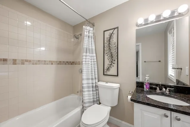 a bathroom with a granite countertop sink toilet a mirror and a bathtub