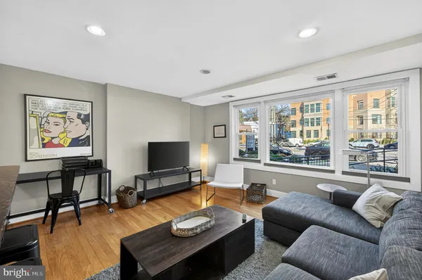 a living room with furniture and a flat screen tv with kitchen view