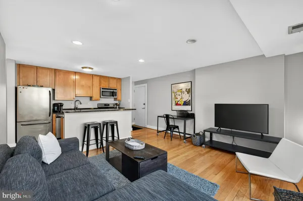 a living room with furniture and a flat screen tv with kitchen view