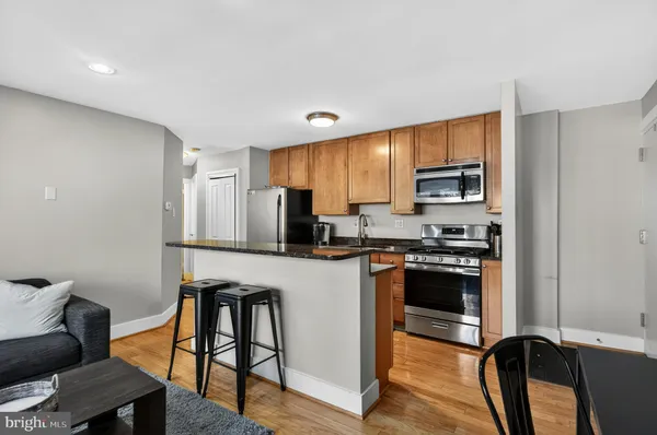 a kitchen with stainless steel appliances granite countertop a stove a sink a refrigerator a dining table and chairs with wooden floor