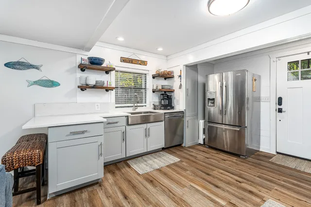 a kitchen with a white refrigerator oven a sink dishwasher and white cabinets with wooden floor