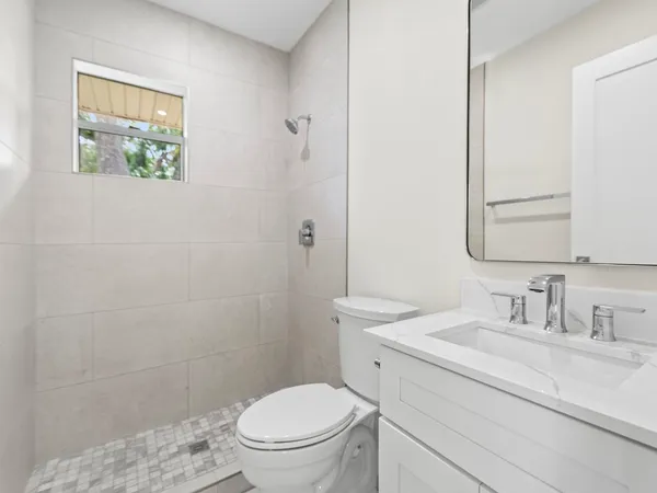 a bathroom with a toilet sink vanity and mirror
