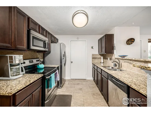 a kitchen with stainless steel appliances granite countertop a sink stove oven granite counter tops and a view of living room