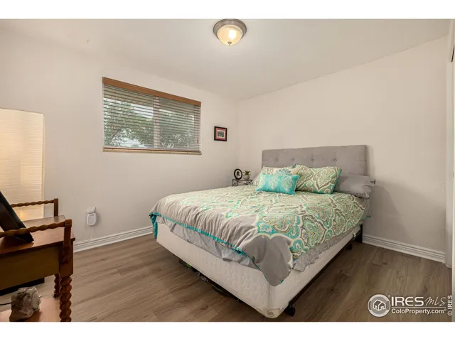a bedroom with a bed window and wooden floor