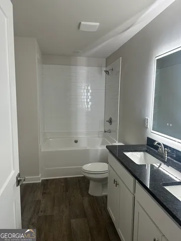 a bathroom with a granite countertop sink a toilet a mirror and shower