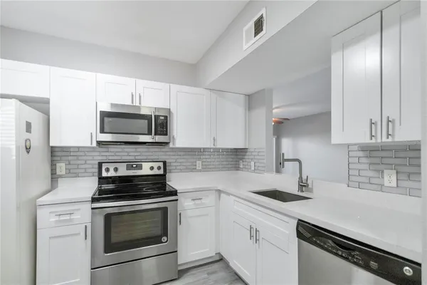 a kitchen with white cabinets stainless steel appliances and sink